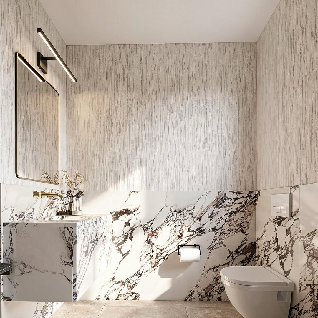 Why is it called a βpowder roomβ instead of just a bathroom?
Centuries ago, it was a space where guests would step away to refresh, compose themselves, and return to the gathering. Today, the idea remains the same, just reimagined through architecture, lighting, texture, and detail.
In this space, soft wall textures meet dramatic stone veining and warm brass accents to create something more than functional. A small room designed to leave a lasting impression.